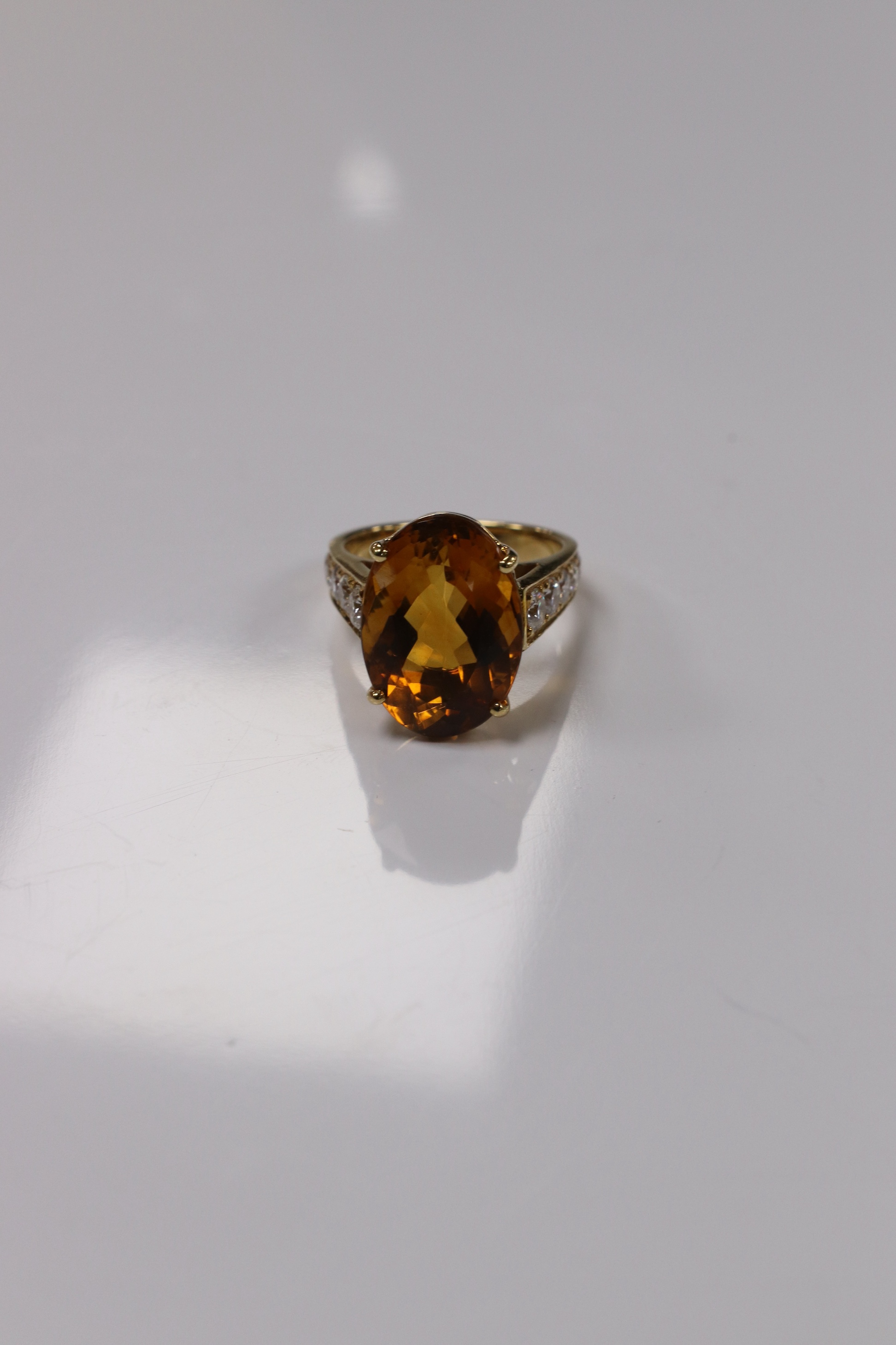 A modern 18k and single stone oval cut citrine set dress ring, with ten stone graduated diamond set shoulders, size K, gross weight 7,7 grams. Condition - good